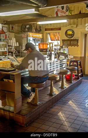 Ein Kunde in einem mexikanischen Restaurant in Merced, Kalifornien, liest beim Essen an der Theke. Stockfoto