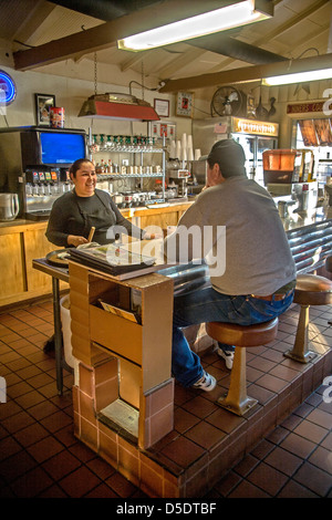 Ein Kunde in einem mexikanischen Restaurant in Merced, Kalifornien, plaudert mit der Inhaber beim Essen an der Theke. Stockfoto