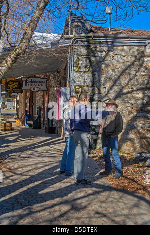 Überschattet von Ästen, unterhalten drei einheimische Männer außerhalb einer alten altmodischen Gemischtwarenladen und Theater im Vulkan, CA. Stockfoto