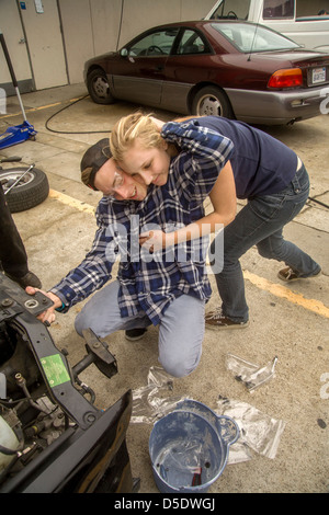 Ein Teen paar, beide sind Studierende der Extraklasse Gymnasium Auto Shop in San Clemente, Kalifornien, teilen eine Umarmung. Stockfoto