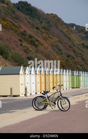 zwei Fahrräder vor Schattierungen von Beige, gelb und grün Strandhütten in Boscombe Bournemouth im März Stockfoto