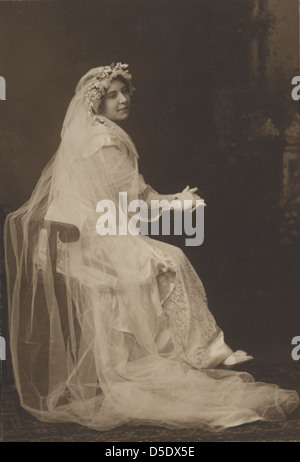 Ein Vintage-Schwarz-weiß-Porträt einer Braut, möglicherweise aus den späten 1800er Jahren, in traditioneller Hochzeitskleidung mit Schleier und Kranz gekleidet. Dieses Foto zeigt einen Moment nachdenklicher Besinnung und spiegelt die Bräuche und den Stil der Hochzeitszeremonien während dieser Zeit wider. Stockfoto