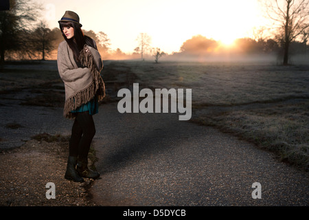 Frau stehend verpackt Shaw am frühen Morgen im Feld Stockfoto