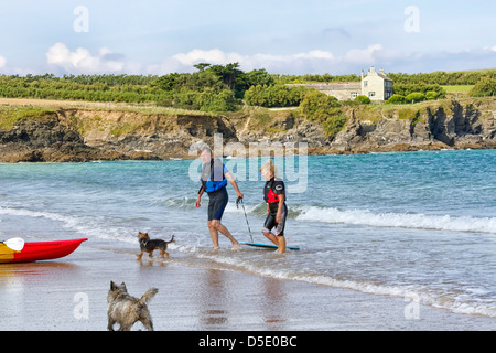 Reifer Mann und Frau mit einem Kanu und zwei Hunden, Harlyn Bay, Cornwall, England Stockfoto