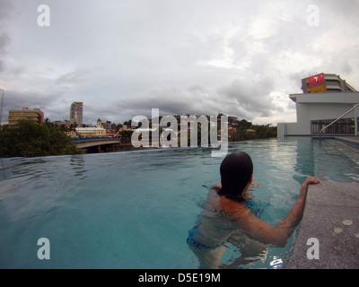 Frau im Hotel-Pool mit Blick auf Townsville am Abend, Queensland, Australien. Keine PR oder Herr Stockfoto