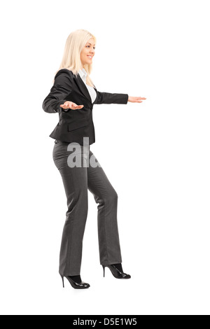 In voller Länge Portrait von eine Geschäftsfrau, die versuchen, Balance, isoliert auf weißem Hintergrund zu halten Stockfoto
