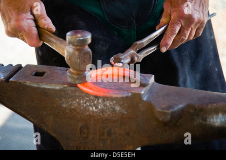 Hufschmied bilden rote heiße Hufeisen mit Hammer auf dem Amboss. Brentwood, Kalifornien, USA. Stockfoto