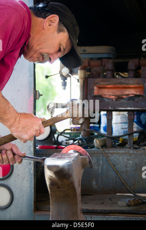 Hufschmied bilden rote heiße Hufeisen mit Hammer auf dem Amboss. Brentwood, Kalifornien, USA. Stockfoto