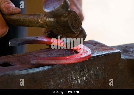 Hufschmied bilden rote heiße Hufeisen mit Hammer auf dem Amboss. Brentwood, Kalifornien, USA. Stockfoto