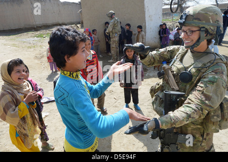 UNS Air Force Staff Sgt Elizabeth Rosato, hält Mitglied des 755. Expeditionary Forces Staffel Reaper Sicherheitsteams mit einheimischen Kindern während einer Patrouille Dorf 11. März 2013 in der Nähe von Bagram Airfield, Afghanistan zu spielen. Reaper-Team führt Patrouillen in der Nähe von Bagram Airfield gegen improvisierte Sprengkörper und indirektes Feuer-Attacken sowie hinsichtlich der einheimischen Unterstützung zu engagieren, im Schutz der Basis. Stockfoto