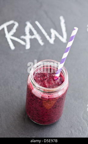 Nahaufnahme von Blueberry Smoothie aus Glas mit gestreiften Stroh mit rohen Wort geschrieben in Kreide auf Hintergrund Stockfoto