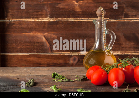 nasse rote Kirschtomaten auf Holztisch mit Olivenöl in Vintage Glasflasche Stockfoto