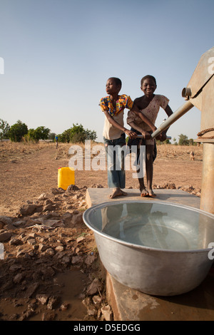 Kinder ziehen Wasser aus einer Bohrung in der Nähe des Dorfes Nandom im Norden Ghanas. Stockfoto