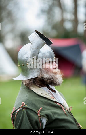 Mittleren Alter Mann mit Bart, gekleidet in mittelalterliche Kleidung und Helm auf ein Re-Enactment-Wochenende in Essex. Seite Ansicht Profilbildnis. Stockfoto