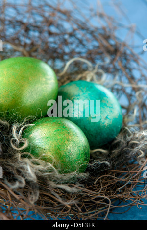 Bunte Ostereier im Nest auf blauem Hintergrund Stockfoto