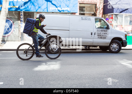 Junger Mann, Blick auf das Handy während der Fahrt ein Fahrrad auf der Straße von New York City, New York Stockfoto