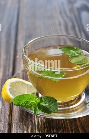 Tee in Tasse mit Minze und Zitrone auf hölzernen Hintergrund Stockfoto
