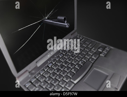 Die Waffe bricht den Laptop-Bildschirm und geht durch ihn. Low-Key, Seitenansicht Stockfoto