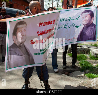 Kaschmir, Indien. 1. April 2013. Mohammad Ahsan Untoo, eine menschliche Rechte Aktivist tragen Ketten wie er einen Banner mit einem senior Kashmiri Separatistenführer während einer Protestaktion gegen illegale Inhaftierung von Kaschmiris und Kashmiri hält Saparatist Führer. Viele separatistische Führer und Aktivisten wurden vor kurzem festgenommen, von der indischen Polizei zu hindern, organisieren Proteste in der Nachfrage der sterblichen Überreste eines muslimischen Kaschmir Mohammad Afzal Gurus, hingerichtet und begraben in einem Hochsicherheits-Gefängnis in Delhi am 9. Februar 2013, wieder. Angriff auf Indiens parl Stockfoto