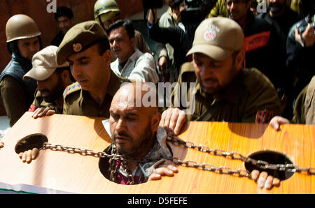 Kaschmir, Indien. 1. April 2013. Indische Polizei verhaften Mohammad Ahsan Untoo, eine menschliche Rechte Aktivist tragen Ketten wie hält er einen Banner mit einem senior Kashmiri Separatistenführer während einer Protestaktion gegen illegale Inhaftierung von Kaschmiris und Kashmiri Saparatist Führer. Viele separatistische Führer und Aktivisten wurden vor kurzem festgenommen, von der indischen Polizei zu hindern, organisieren Proteste, die sterblichen Überreste eines muslimischen Kaschmir Mohammad Afzal Guru herauszuverlangen, hingerichtet und begraben in einem Hochsicherheits-Gefängnis in Delhi am 9. Februar 2013. Stockfoto