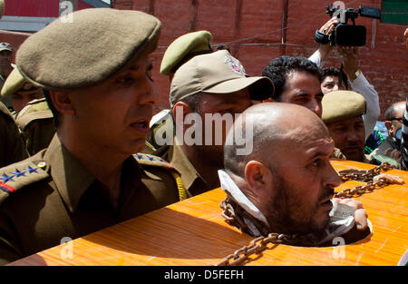 Kaschmir, Indien. 1. April 2013. Indische Polizei verhaften Mohammad Ahsan Untoo, eine menschliche Rechte Aktivist tragen Ketten wie hält er einen Banner mit einem senior Kashmiri Separatistenführer während einer Protestaktion gegen illegale Inhaftierung von Kaschmiris und Kashmiri Saparatist Führer. Viele separatistische Führer und Aktivisten wurden vor kurzem festgenommen, von der indischen Polizei zu hindern, organisieren Proteste, die sterblichen Überreste eines muslimischen Kaschmir Mohammad Afzal Guru herauszuverlangen, hingerichtet und begraben in einem Hochsicherheits-Gefängnis in Delhi am 9. Februar 2013. Stockfoto