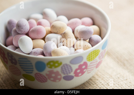 Eine Schüssel mit Mini Ostereier, auf braunem strukturiertem Hintergrund Stockfoto