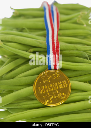 grüne Bohnen mit Goldmedaille Sieger Anhänger an einem hölzernen Hintergrund Stockfoto