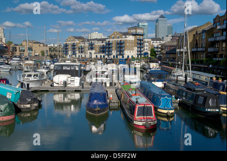 Schmale Boote ankern in Limehouse Bassin mit Wohnungen und Canary Wharf in den Hintergrund, London, UK Stockfoto