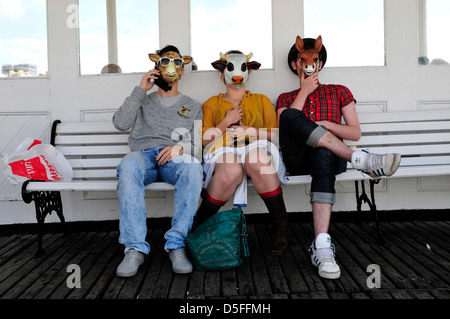 Drei Leute sitzen auf einer Bank tragen Masken, Pier von Brighton, Vereinigtes Königreich. Stockfoto