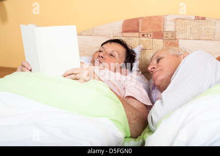 Nahaufnahme von zwei Senioren Buch im Bett lesen. Stockfoto