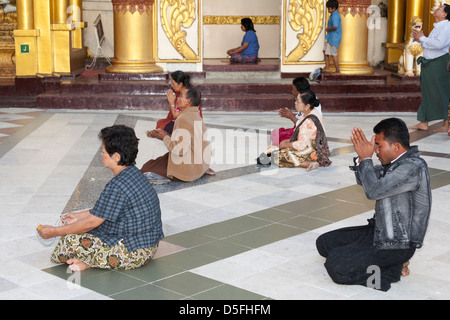 Gläubige beten außerhalb einen Betsaal an der Shwedagon-Pagode, Yangon (Rangoon), Myanmar (Burma) Stockfoto