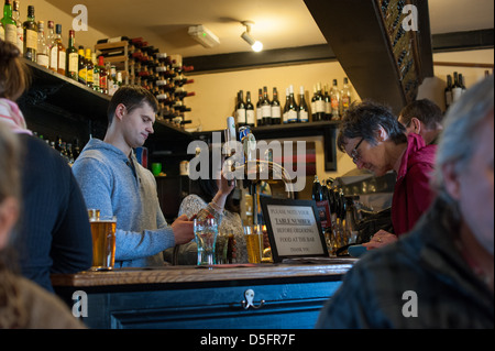 Junge weiße bar Mann Bierausschank, eine ältere Frau in einem englischen Pub an einem Wintertag mit Getränken an der bar Stockfoto