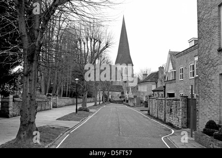 Ein schwarz / weiß Bild einer von Bäumen gesäumten Straße führt an Str. Marys Kirche im Hintergrund Horsham Sussex England Stockfoto