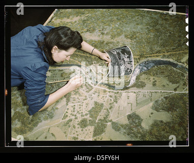 Camouflage-Klasse an der N[ew] Y[ork] University, wo Männer und Frauen sich auf Jobs in der Armee oder in der Industrie vorbereiten, New York, N.Y. Dieses Modell wurde getarnt und fotografiert. Das Mädchen korrigiert Überblicke, die in der Tarnung eines Modells entdeckt wurden Stockfoto