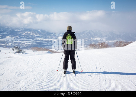 Rückseite des weiblichen Skifahrer wie sie sich auf eine frisch präparierte Piste in leichter Schneefall begibt. Stockfoto