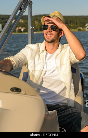 Mann mit Sonnenbrille und Strohhut Navigation Boot Sonnentag Stockfoto