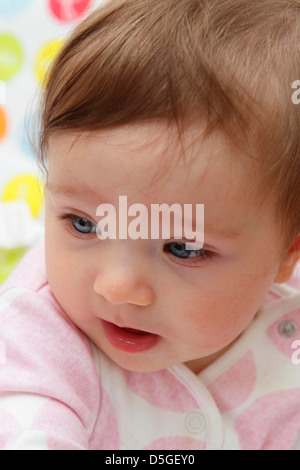 Acht Monate altes Baby Mädchen tragen rosa Strampler in ihrem Hochstuhl auf ihr erstes Ostern abgebildet. Stockfoto