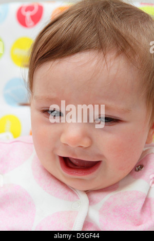 Acht Monate altes Baby Mädchen tragen rosa Strampler in ihrem Hochstuhl auf ihr erstes Ostern abgebildet. Stockfoto