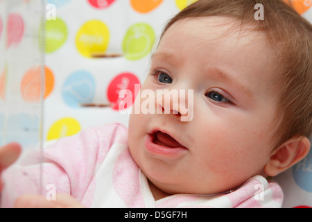 Acht Monate altes Baby Mädchen tragen rosa Strampler in ihrem Hochstuhl auf ihr erstes Ostern abgebildet. Stockfoto