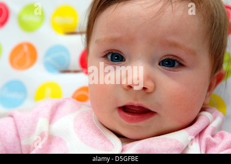Acht Monate altes Baby Mädchen tragen rosa Strampler in ihrem Hochstuhl auf ihr erstes Ostern abgebildet. Stockfoto