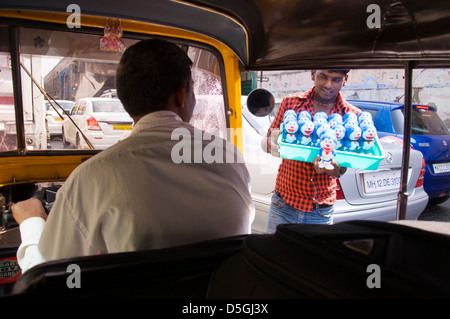 Junger Mann verkaufen mechanisches Spielzeug bietet Tuk Tuk Fahrer im Stau in Mumbai Stockfoto