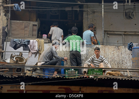 Eine Gruppe indischer Jugendlicher sitzt auf Kisten auf einem Dach und Balkon über den Geschäften in Chandni Chowk, Alt-Delhi, Indien Stockfoto