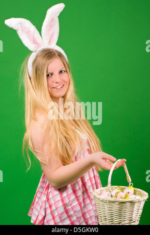 Junge blonde Frau in einem rosa Kleid präsentieren Ostern Eiern in einem Korb Stockfoto