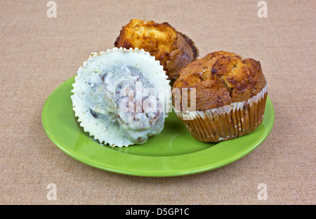 Drei frisch gebackene Muffins auf grünem Teller mit Tuch Hintergrund. Stockfoto
