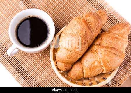 Frische und leckere französische Croissants in ein Korb und eine Tasse Kaffee serviert isolierten auf weißen Hintergrund Stockfoto