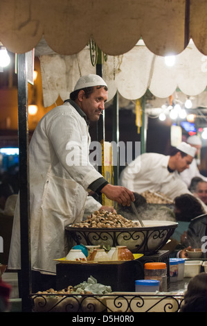 Mann, Verkauf von Schnecken aus einem Stall in dem Djemaa el-Fna-Platz in der Nacht, Marrakesch, Marokko