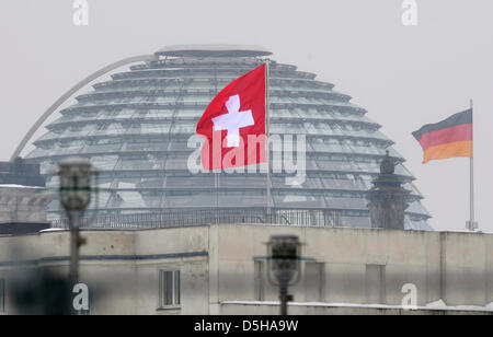 Die Schweizer Flagge Wellen auf dem Dach des Schweizer Botschaft nach Deutschland vor deutschen Fähnchen auf Reichstagsgebäude in Berlin, Deutschland, 4. Februar 2010. Ein anonymer Informant angeboten eine CD mit Daten von 1.500 deutschen Steuersündern, die Bundesregierung zu einem Preis von 2,5 Millionen Euro. Bundeskanzlerin Merkel und Innenräume Minster Schäuble grünes Licht umstrittenen kaufen Stockfoto