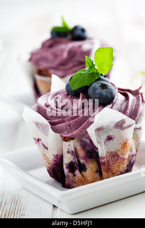 Blaubeer-Muffins mit Zuckerguss, Blaubeeren und Minze Blätter Stockfoto