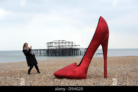 Ein riesigen roten Stiletto Schuh Aufsehen für Läufer am frühen Morgen und Passanten auf Brighton Seafront heute als es im Rahmen von Churchill Square Shopping Centre der erschien, wenn der Schuh passt Veranstaltung stattfindet über die nächsten paar Tage halten. Stockfoto