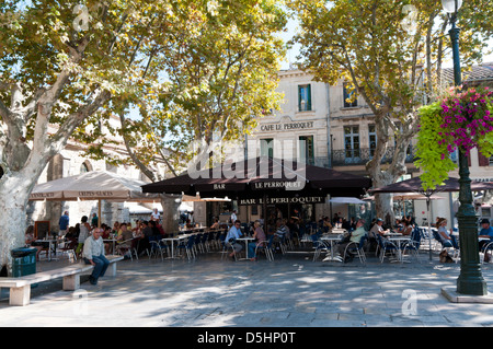 Menschen sitzen im Café Tische unter den Bäumen in einem Quadrat in der alten Stadt Aigues-Mortes. Stockfoto